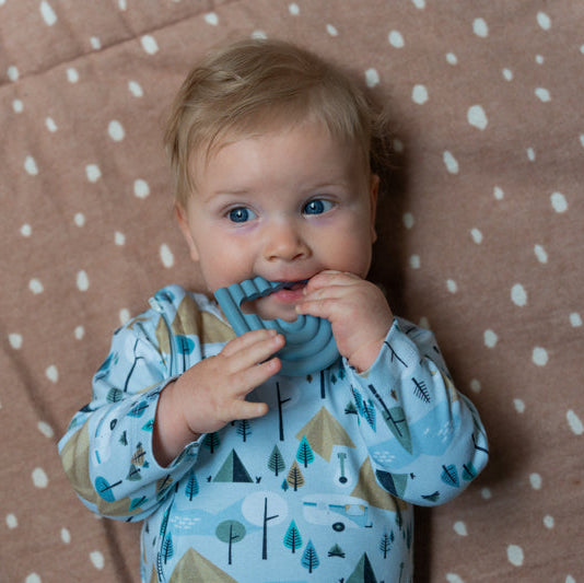 Baby wearing camping romper chewing on cloud teether