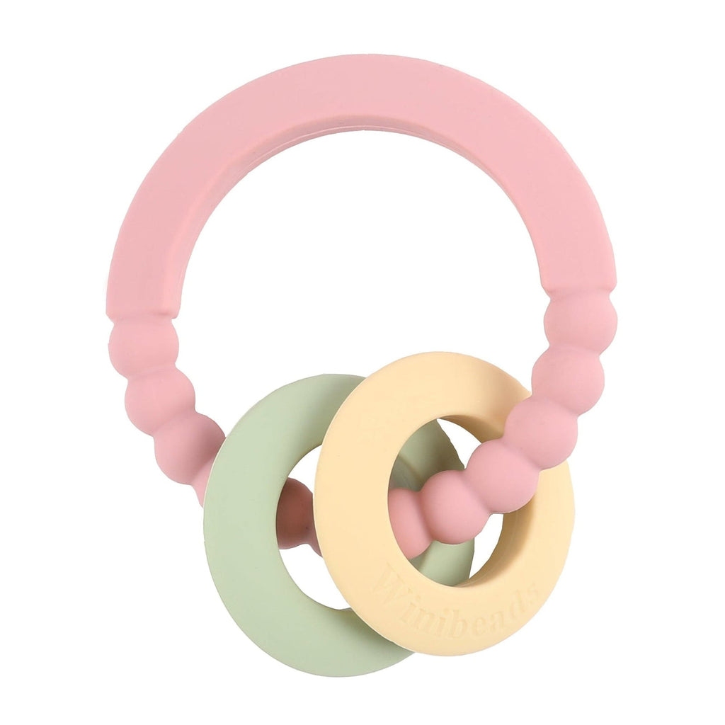 Pink, green, and yellow baby teething ring on a white background