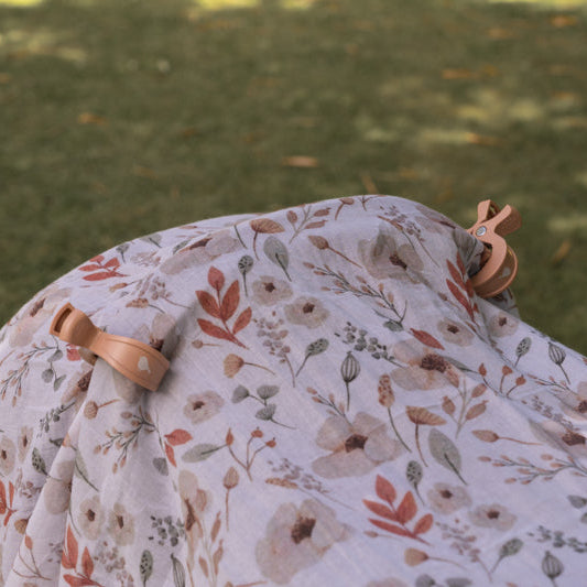 Boho Muslin and pram clips attached to  baby carrier on grass
