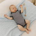 Baby lying on a textured blanket with a pacifier nearby