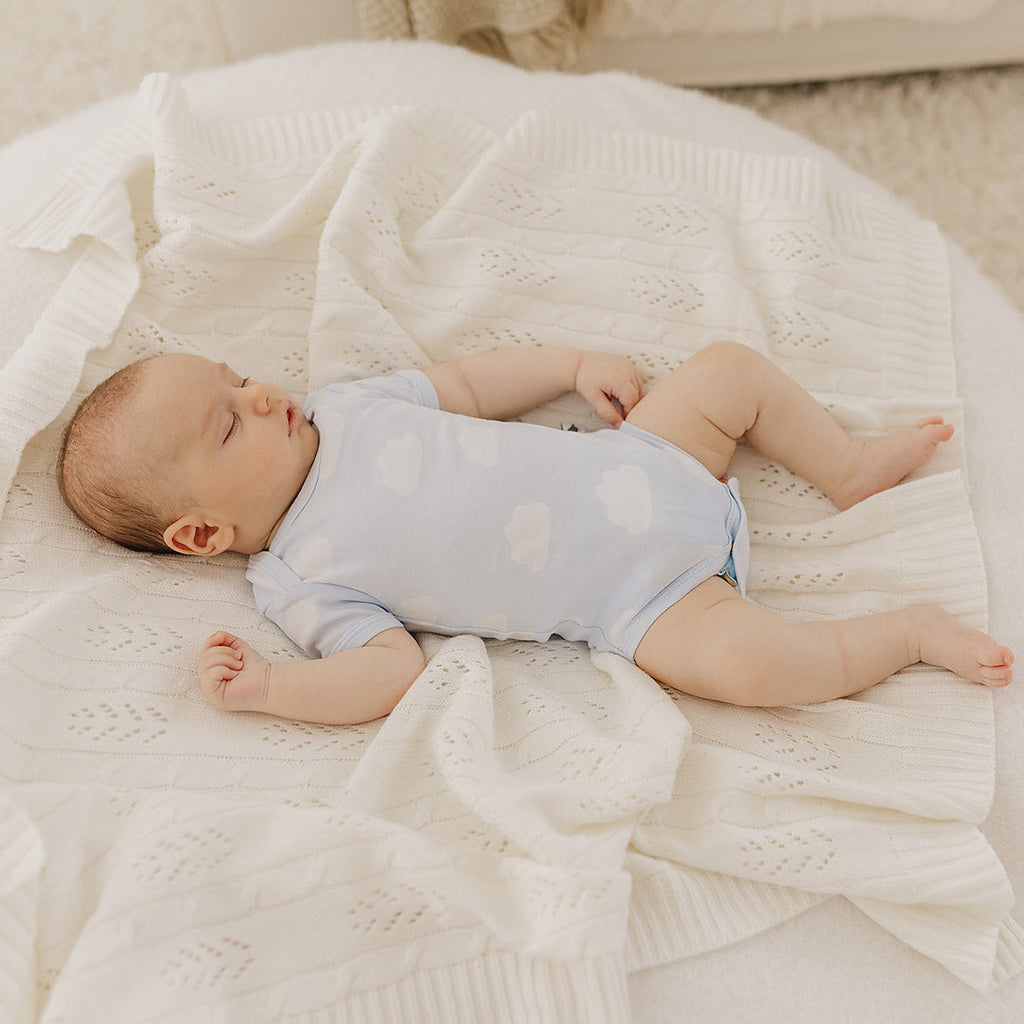 Baby lying on a white blanket in a cozy setting